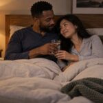 Couple adulte en vêtements de nuit partageant un verre d'eau et un moment tendre dans un lit